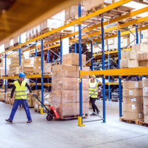 Magazijn waarin twee magazijnmedewerkers een palletwagen vol dozen verplaatst