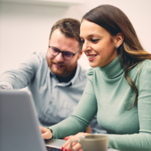 Twee tevreden officemedewerkers analyseren de positieve resultaten en real-time data van de scanoplossing op een computerscherm