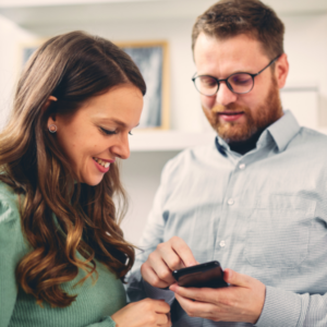 Twee kantoormedewerkers bekijken samen de overzichtelijke Modest registratie-app op een smartphone in een kantooromgeving